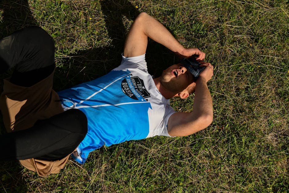 A man lies on green grass outdoors with covered eyes, conveying relaxation.