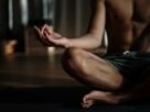 A shirtless man in a yoga studio meditating in the lotus position for relaxation and wellness.
