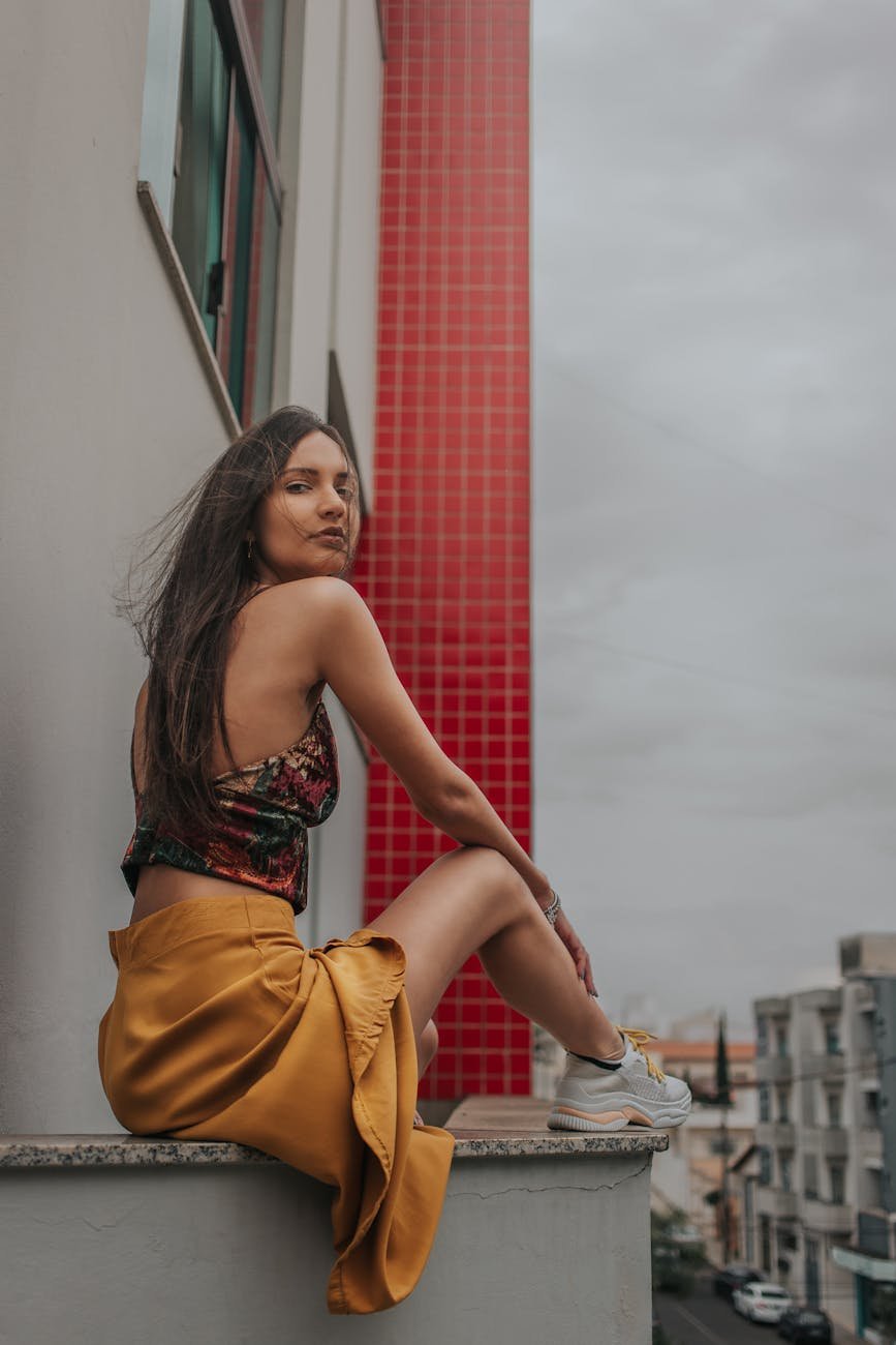 A young woman in fashionable attire poses against a city backdrop in Passos, MG, Brazil.