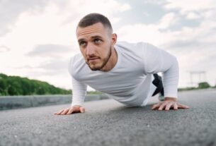 Focused man in sportswear doing push-ups on a road in a natural setting.