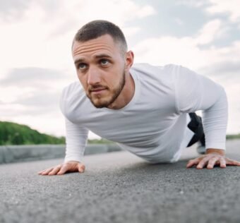 Focused man in sportswear doing push-ups on a road in a natural setting.