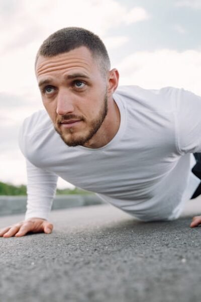 Focused man in sportswear doing push-ups on a road in a natural setting.